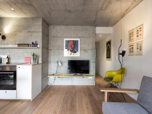 a living room with a couch and a tv on a wall at FRIZ Holiday Apartments in Gundelfingen