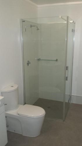 a bathroom with a toilet and a glass shower at Onslow Apartments in Onslow