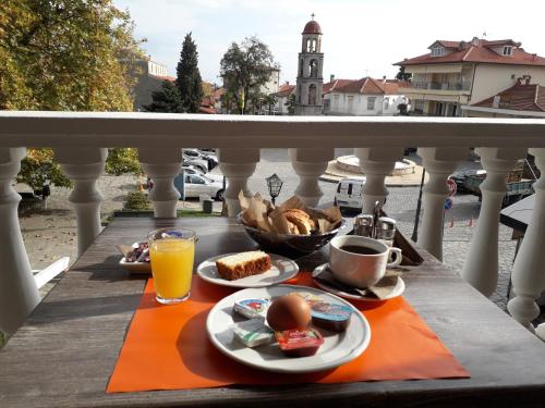 a breakfast on a balcony with food and orange juice at Olympus View Rooms Sauna & Spa in Litochoro