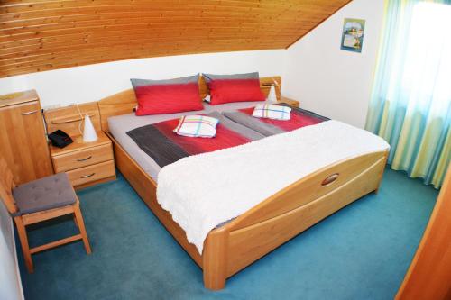 Un dormitorio con una gran cama de madera con almohadas rojas en Haus Sonnenhügel en Winterberg