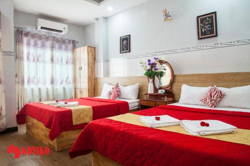 Habitación de hotel con 2 camas con sábanas rojas en Koniko Hotel, en Ho Chi Minh