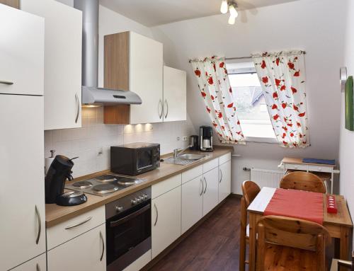 eine Küche mit weißen Schränken, einem Tisch und einem Fenster in der Unterkunft fewo-wachtendonk in Wachtendonk