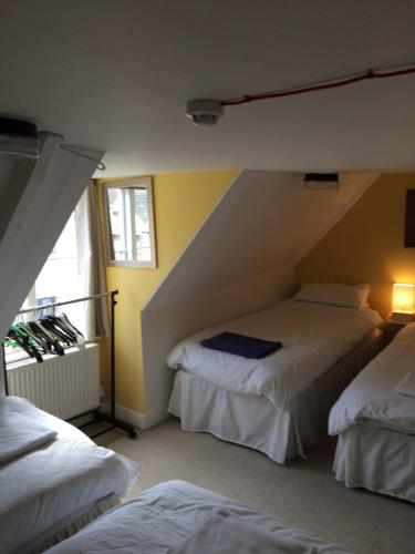 a attic room with two beds and a window at Sailors Return Weymouth in Weymouth