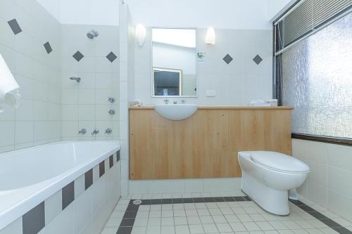 a bathroom with a tub and a toilet and a sink at Banksia Motel in Collie