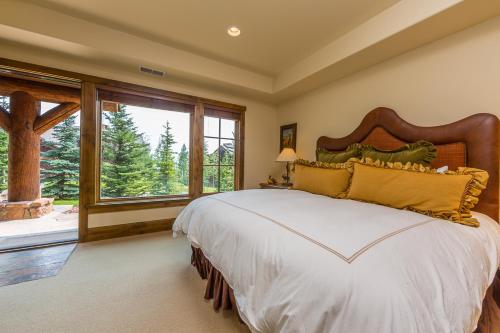 a bedroom with a large bed and a large window at Spanish Peaks Settlement Cabin in Big Sky