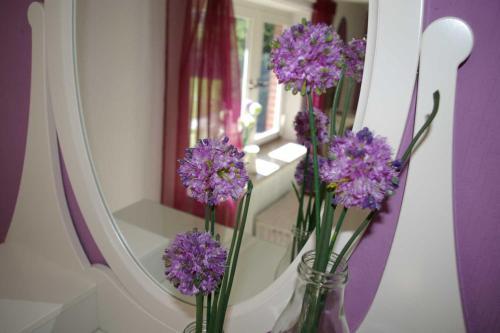 un vaso con fiori viola davanti a uno specchio di Ferienhaus Klookris 15 a Risum-Lindholm