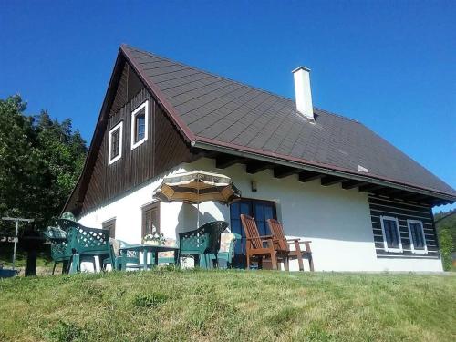 ein Haus mit Stühlen und einem Sonnenschirm davor in der Unterkunft Luxury Chalet in Stupna near Ski area in Stupná