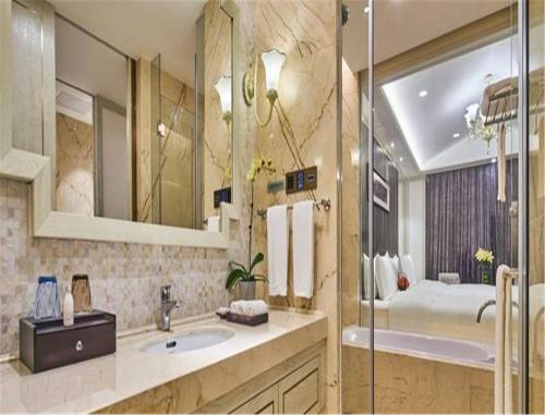 a bathroom with a sink and a tub and a mirror at Wanda Realm Xiamen North Bay in Xiamen