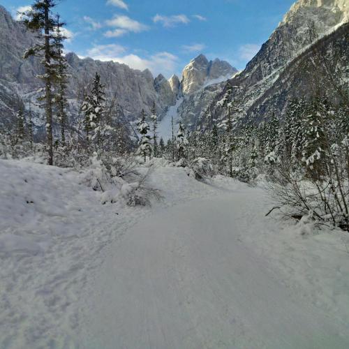 a road covered in snow with mountains in the background at House Neza in Kranjska Gora