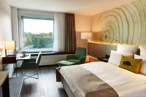 a hotel room with a bed and a chair and a window at Steigenberger Airport Hotel Frankfurt in Frankfurt/Main