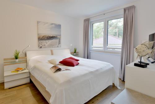 1 dormitorio blanco con 1 cama blanca grande con almohadas rojas en Ferienwohnung Seestern, en Juliusruh