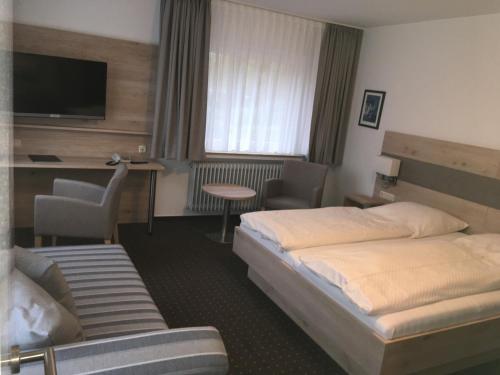 ein Hotelzimmer mit 2 Betten und einem TV in der Unterkunft Hotel Neuenburger Hof in Neuenburg