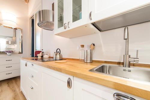 a kitchen with white cabinets and a stainless steel sink at Santa Croce apartment in Florence