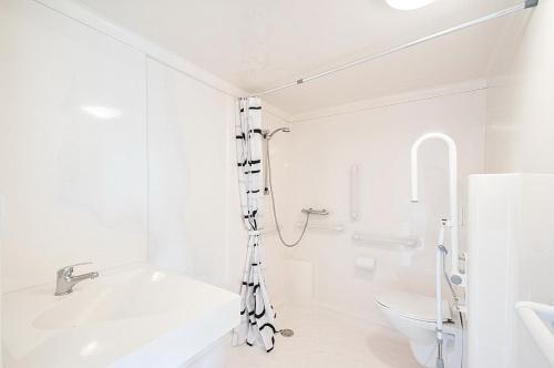 a white bathroom with a shower and a toilet at KustCamp Ekön in Gryt