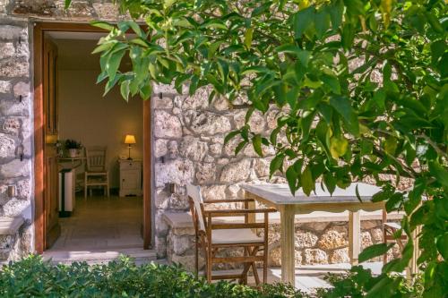 a table and chairs in front of a stone wall at Mare Monte Luxury Suites in Spetses