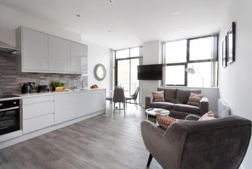 a kitchen and living room with a couch and a table at Cotels 7Zero1 Aparthotel - Unique Apartment building with friendly Reception - Sky Movies & Sports - Fitness Equipment in Apt - Pet Friendly - Private Garden Area in Milton Keynes