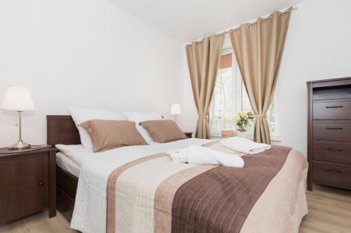 a white bedroom with a large bed and a television at Grace Apartment II in Kołobrzeg
