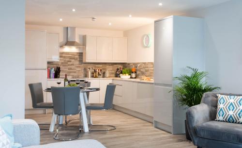 a kitchen and living room with a table and chairs at Cotels 7Zero1 Aparthotel - Unique Apartment building with friendly Reception - Sky Movies & Sports - Fitness Equipment in Apt - Pet Friendly - Private Garden Area in Milton Keynes
