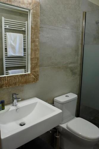 a bathroom with a sink and a toilet and a mirror at Euphoria Retreat in Mánganos