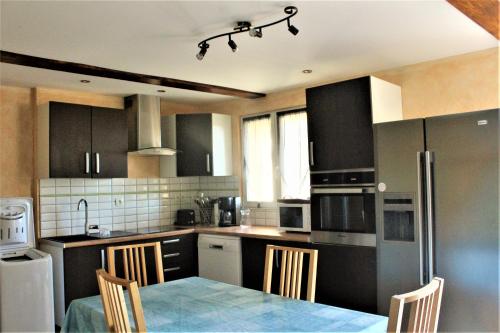 a kitchen with black cabinets and a table with chairs at LOCATIONS RIVES DE SEUGNE - Claveau in Jonzac