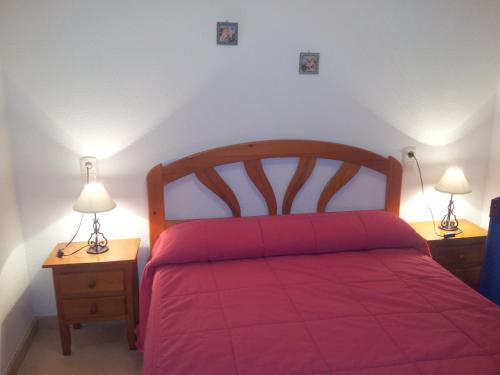 een slaapkamer met een rood bed en 2 nachtkastjes bij Apartamentos Aixa in Caravaca de la Cruz