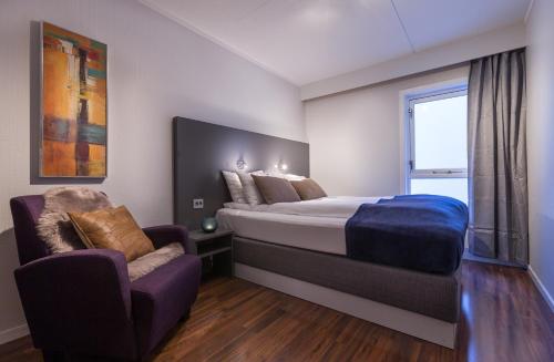a bedroom with a king sized bed and a chair at Enter Viking Hotel in Tromsø