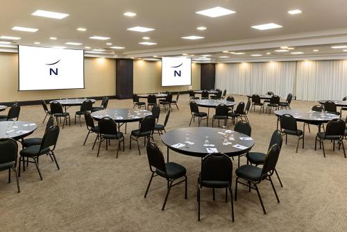 a conference room with tables and chairs and screens at Novotel Sao Paulo Center Norte in Sao Paulo