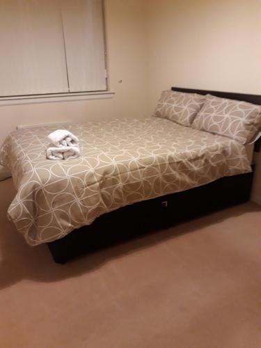 a bed in a room with a white comforter at Handy Dale House in Bathgate