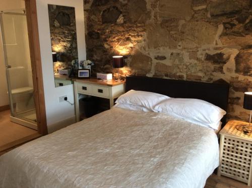 um quarto com uma cama e uma parede de pedra em Comber Courtyard Apartment em Comber