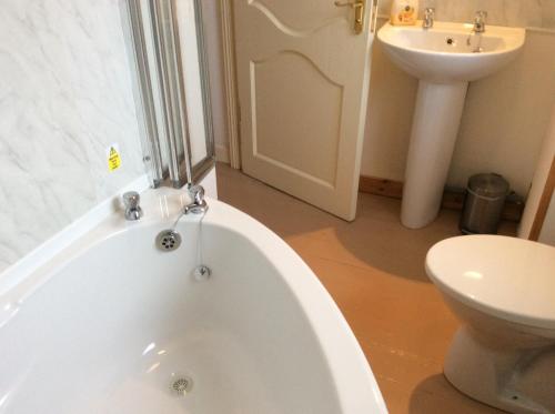 a bathroom with a tub and a sink and a toilet at Comber Courtyard Apartment in Comber