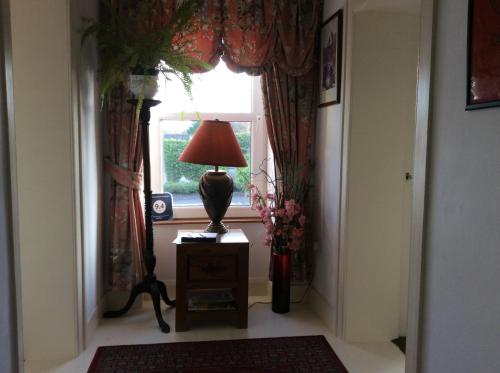 a hallway with a lamp on a table in front of a window at Comber Courtyard Apartment in Comber