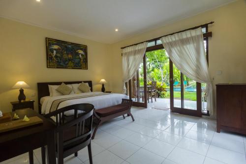 een slaapkamer met een bed, een tafel en een bureau bij Nyoman Sandi Guest House in Ubud