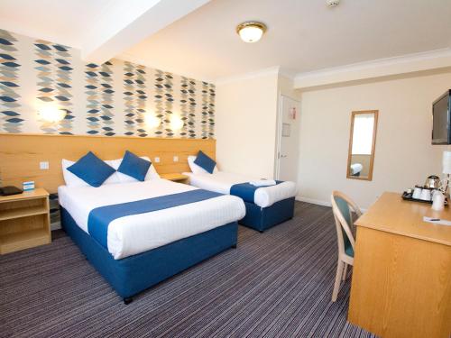 
a hotel room with two beds and a desk at TLH Derwent Hotel (TLH Leisure Resort) in Torquay
