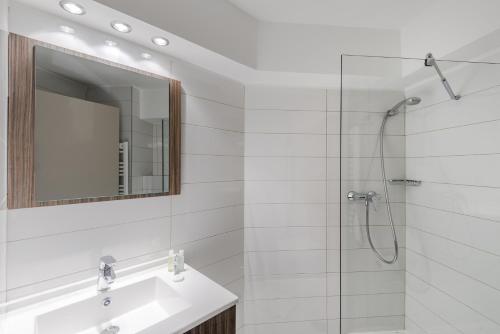 a bathroom with a sink and a shower with a mirror at Appart’hôtel Hevea in Valence