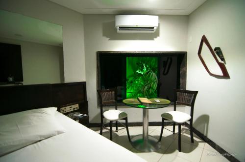 - une chambre avec un lit, une table et des chaises dans l'établissement Toulouse Motel (Adult Only), à Natal