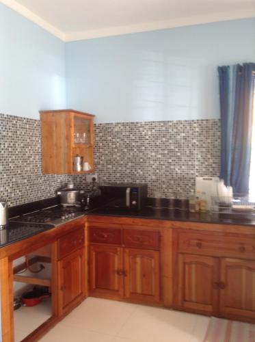 una cocina con armarios de madera y encimeras negras en Beau Vallon Residence en Mahe