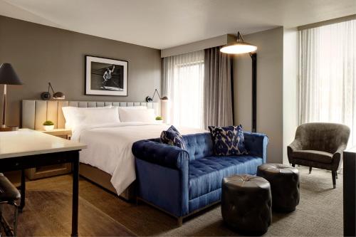 um quarto de hotel com uma cama e um sofá azul em Archer Hotel Florham Park em Florham Park