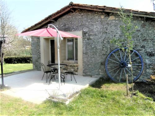 a patio with a table and an umbrella next to a building at LOCATIONS RIVES DE SEUGNE - Claveau in Jonzac