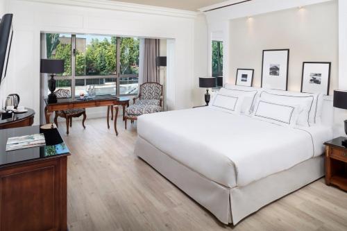 a bedroom with a large white bed and a desk at Melia Barajas in Madrid