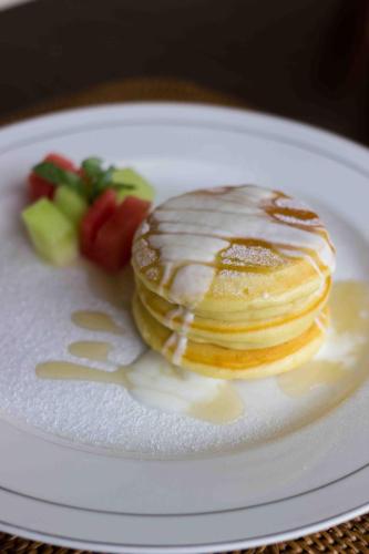 ウブドにあるニョマン サンディ ゲスト ハウスのパンケーキとフルーツが積まれた白い皿