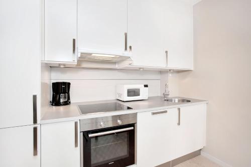 a white kitchen with a sink and a microwave at BJØRVIKA APARTMENTS, Opera Area, Oslo city center in Oslo
