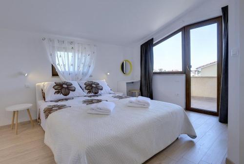 a white bedroom with a large bed with towels on it at Apartments Buic in Vinkuran