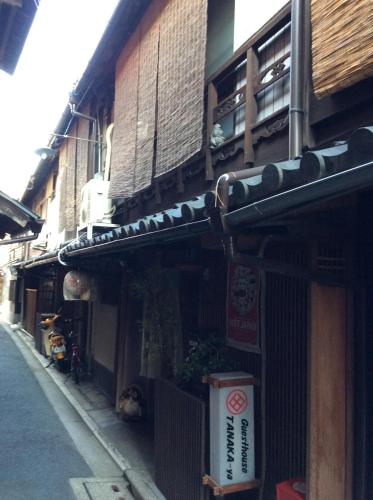 un edificio con un cartello sul lato di una strada di Tanaka-ya a Kyoto