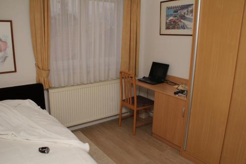 a bedroom with a bed and a desk with a laptop at Hotel Vila Tina in Zagreb