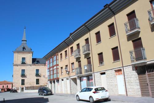 a white car parked in front of a building with a tower at Ático Vista Alegre in Lerma