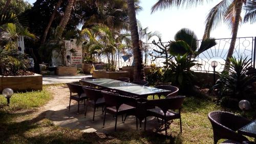 a table and chairs in a yard with palm trees at Sunny Beachfront Studio in Mombasa