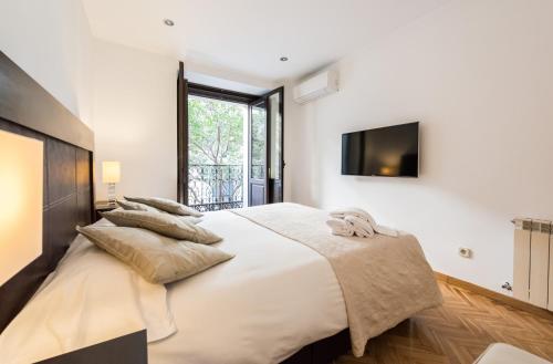 una camera bianca con un grande letto con cuscini di Malasaña Boutique by Madflats Collection a Madrid