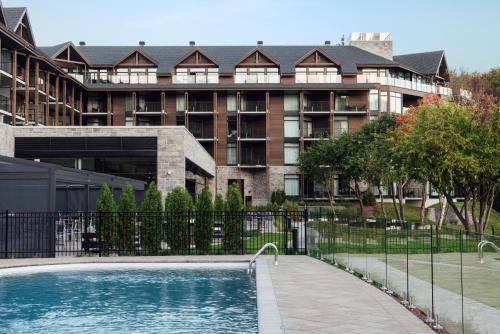 a building with a swimming pool in front of a building at Entourage sur-le-Lac in Lac-Beauport