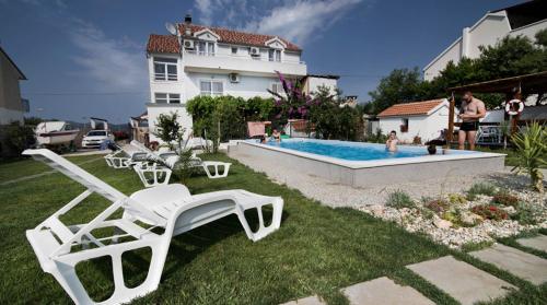 a yard with chairs and a swimming pool at Rooms & Apartments Marinero in Betina