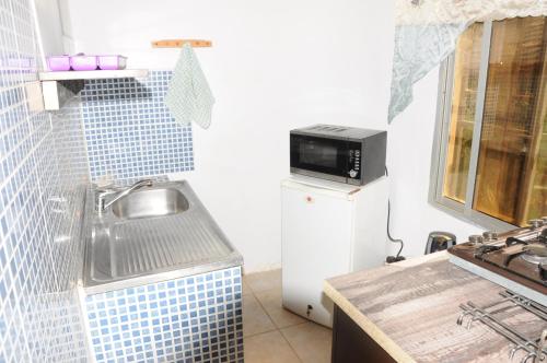a kitchen with a sink and a microwave on a refrigerator at Leybato Beach Hotel in Fajara